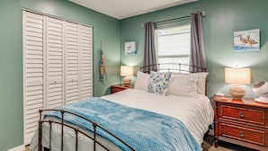 A bedroom with a bed, nightstands, a window with curtains, a wall-mounted lamp, and a painting. - 2 Nature Coast Units w/ Shared Courtyard (Homosassa)