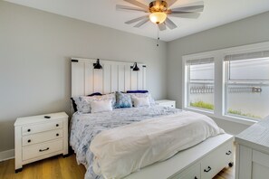 A bedroom with a bed, bedside tables, a ceiling fan, and a window with a view. - Waterfront Home w/ Deck & Views on Copano Bay! (Taft)