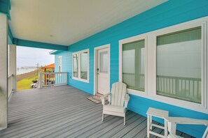 A covered porch with a wooden deck, a white chair, and a small table. - Waterfront Home w/ Deck & Views on Copano Bay! (Taft)