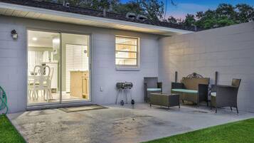 A house with a patio area featuring outdoor furniture and a grill.