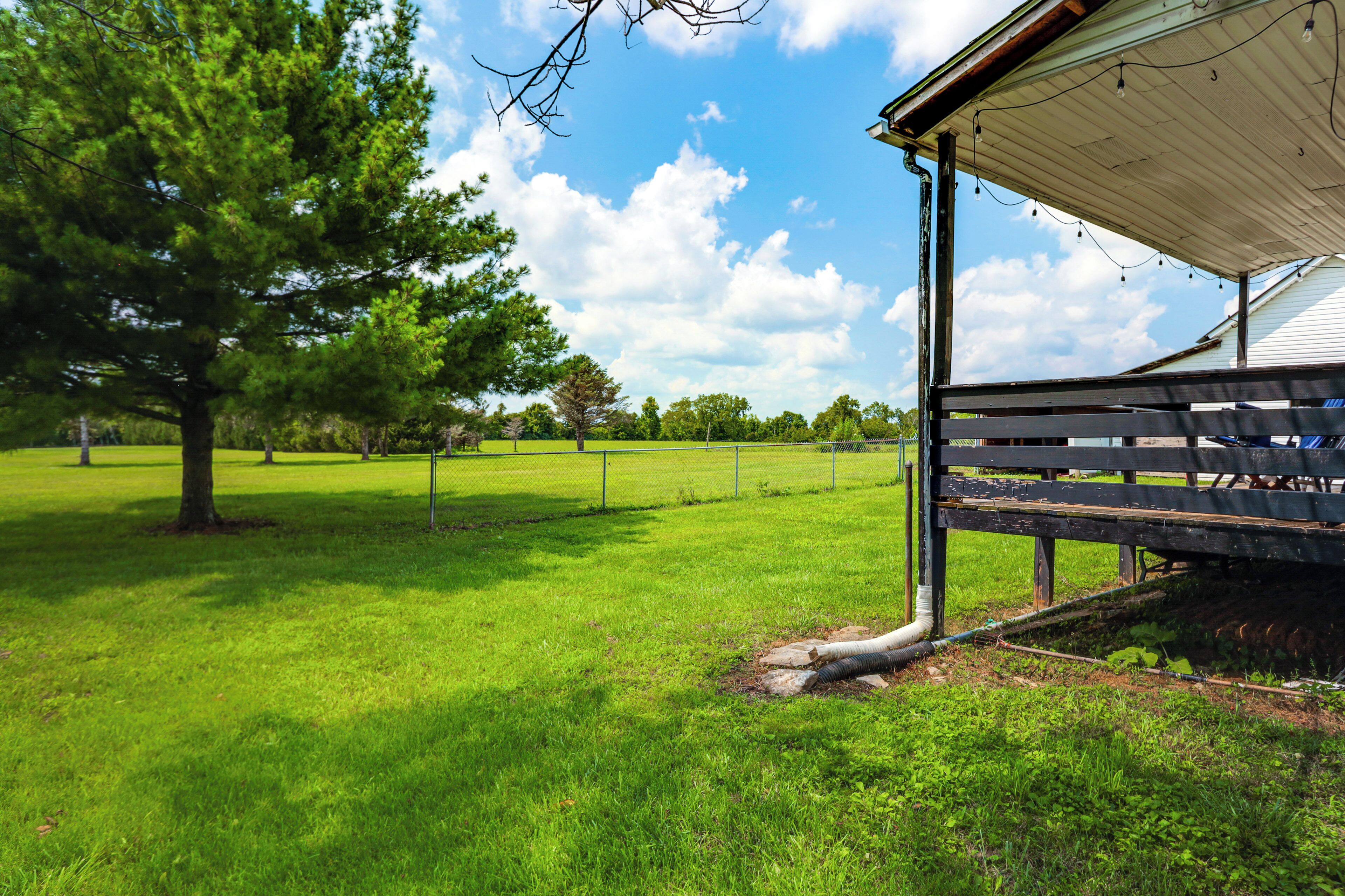 A grassy field with a wooden bench and a covered structure.