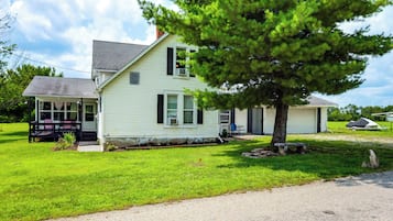 A single-story house with a front porch, a garage, and a tree in the yard.