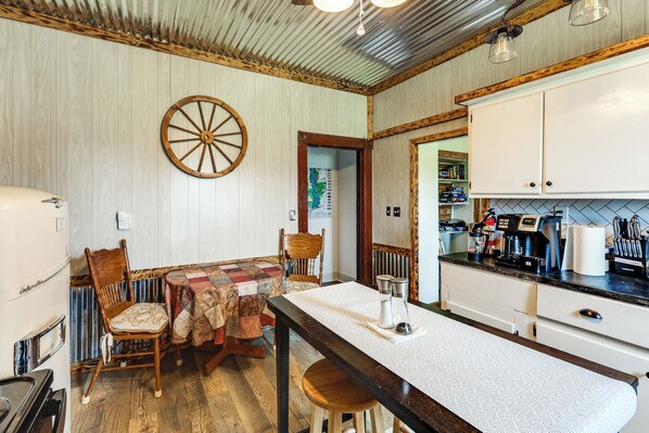 A kitchen with a wooden table, chairs, a refrigerator, and cabinets.
