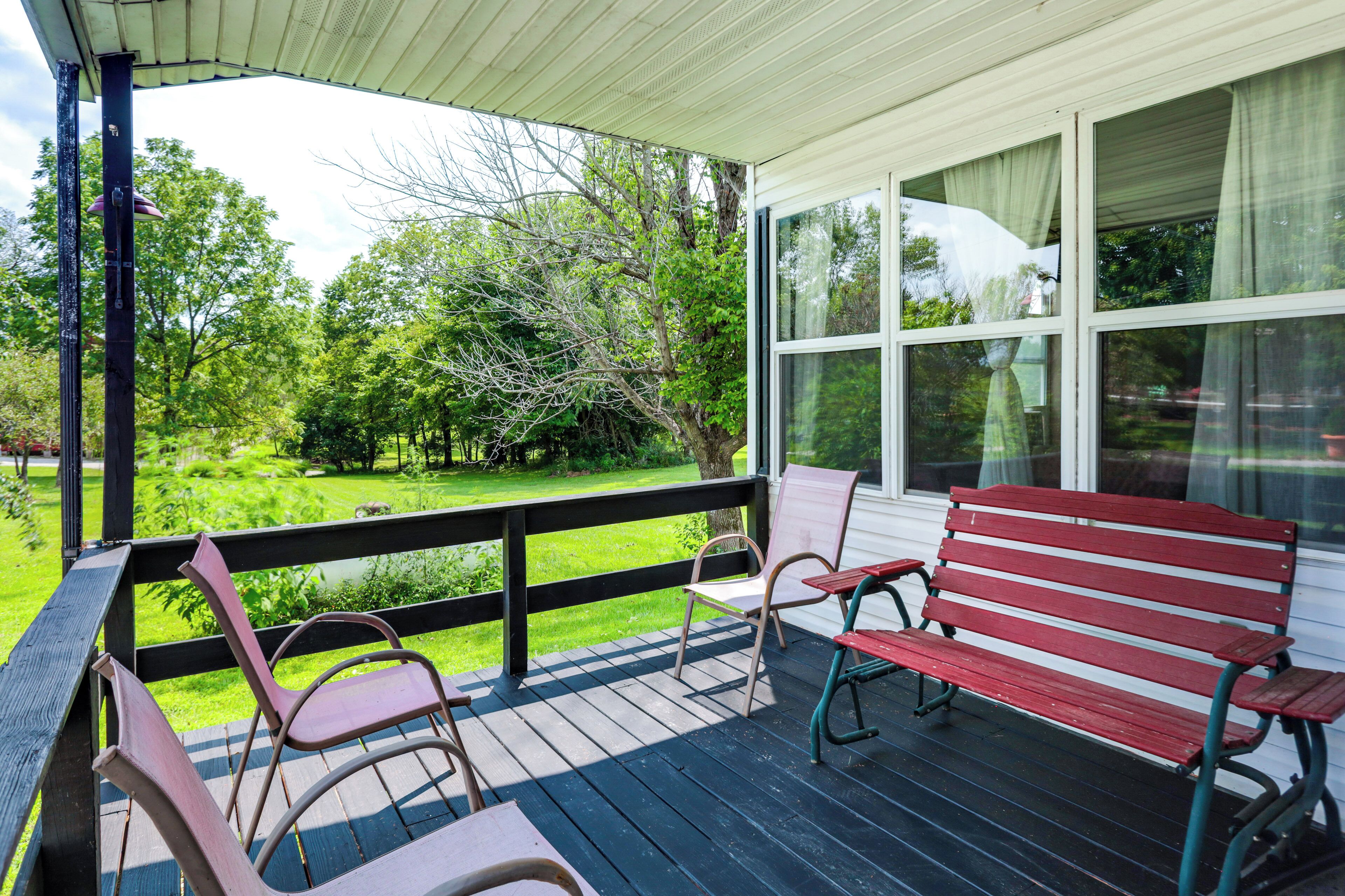 A covered porch with a view of a green landscape.