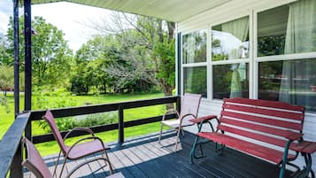 A covered porch with a view of a green landscape.