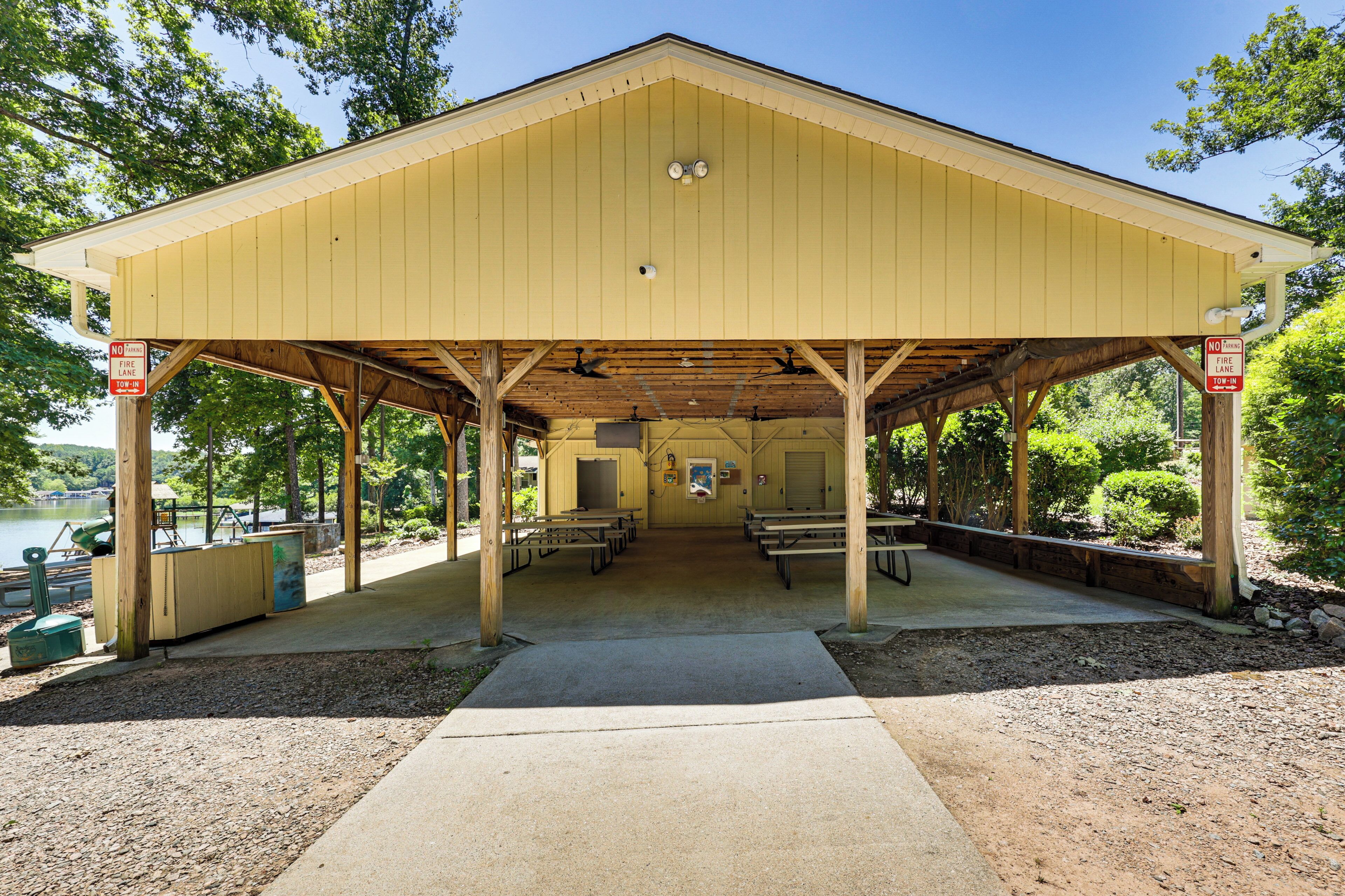A covered picnic area with benches and a concrete path leading to it.