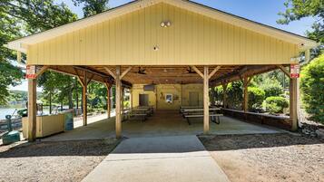 A covered picnic area with benches and a concrete path leading to it.