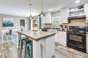 Een moderne keuken met een centraal eiland, hanglampen en een grote oven.