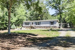 A single-story house with a front porch, a staircase leading to the entrance, and a small yard with a gravel path.