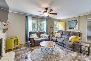 A living room with a fireplace, two sofas, a coffee table, and a ceiling fan.