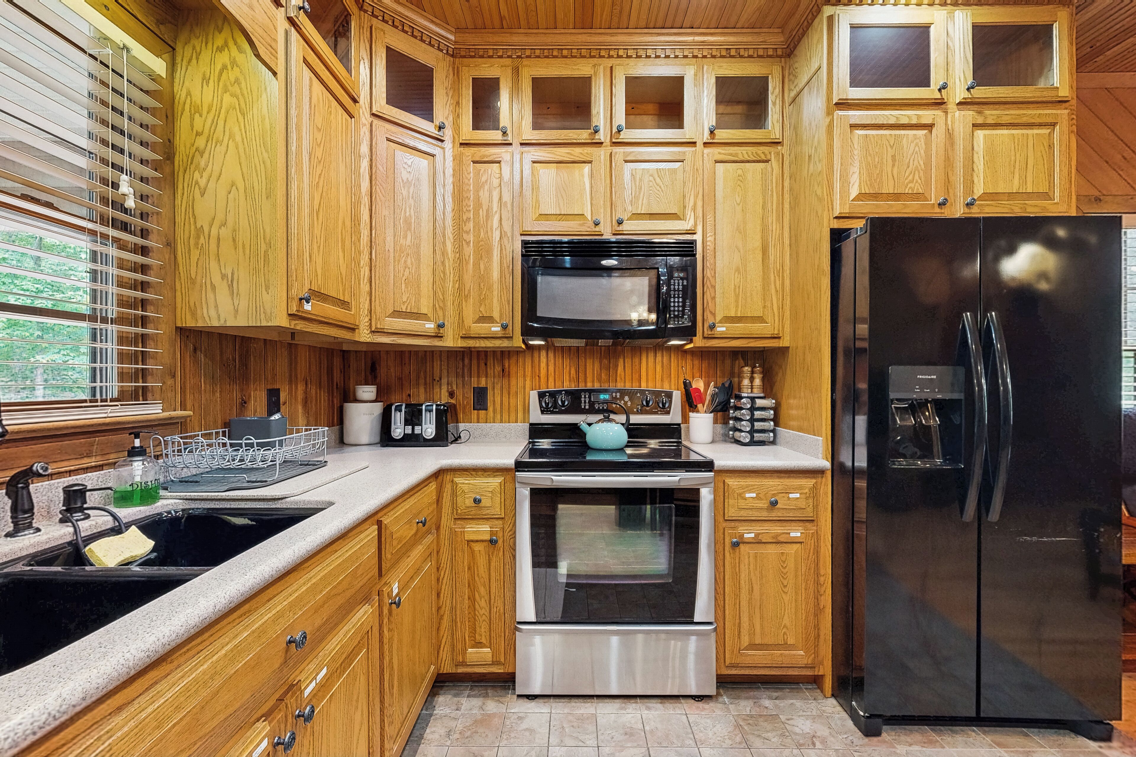 A kitchen with wooden cabinets, a stainless steel oven, a black refrigerator, and a microwave.