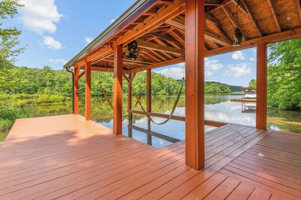 A wooden deck with a clear view of a lake and forested hills.