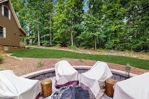An outdoor seating area with covered chairs and a fire pit, surrounded by a well-maintained lawn and trees. - Dock & Fire Pit! Lake Gaston Cabin in Macon (Macon)