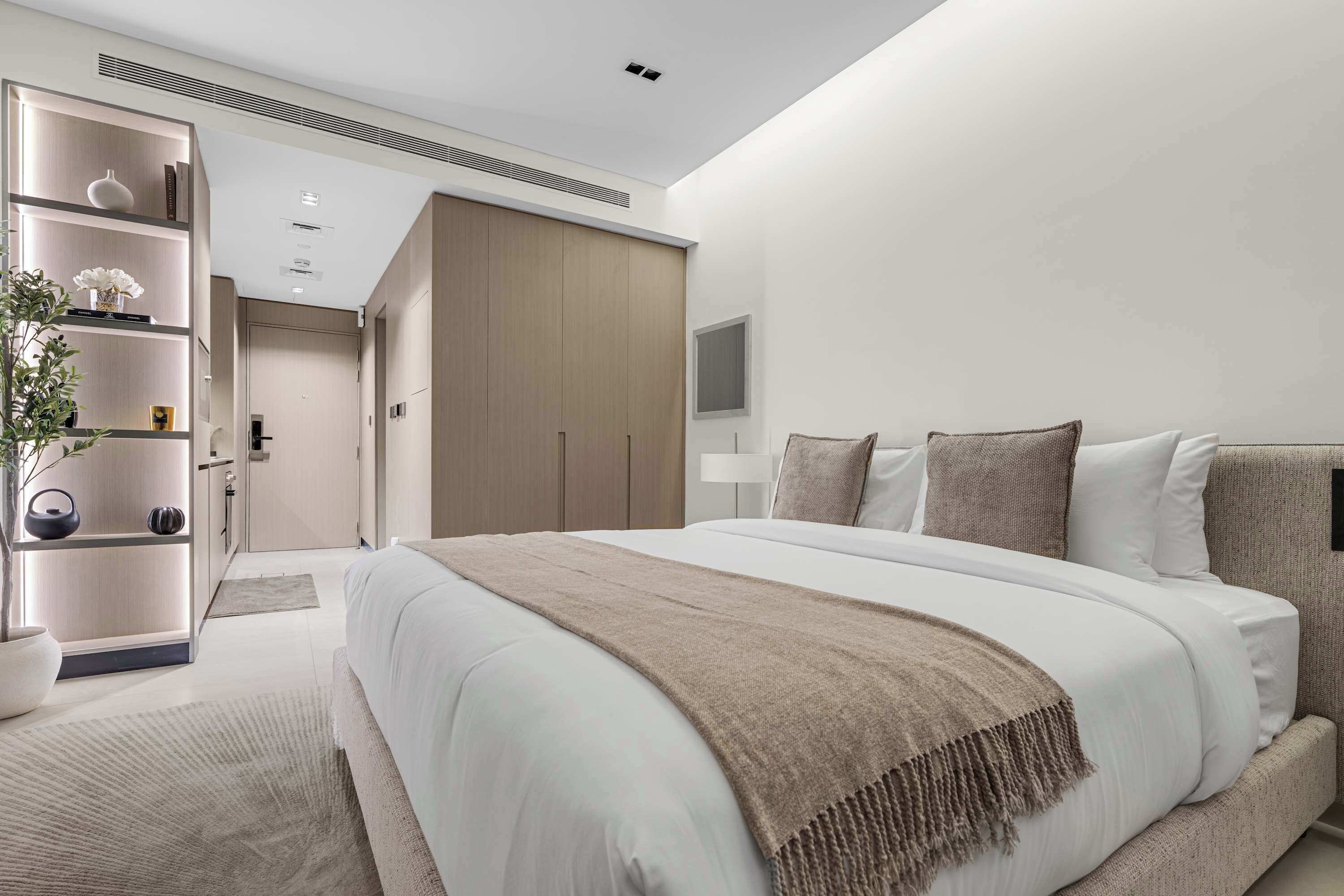 Una moderna camera d'hotel con un letto grande, un armadio, un comodino e una televisione.