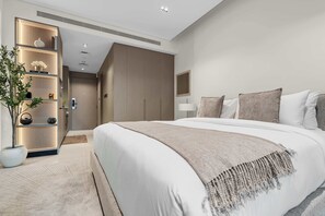 A modern hotel room with a large bed, a bedside table, a lamp, and a plant. - Arjan Studio with Pool View, Jogging Track & BBQ (Arjan)