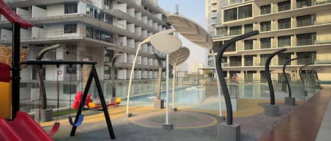 Un espace de jeux pour enfants avec des toboggans et des balançoires, entouré d’immeubles d’appartements modernes.