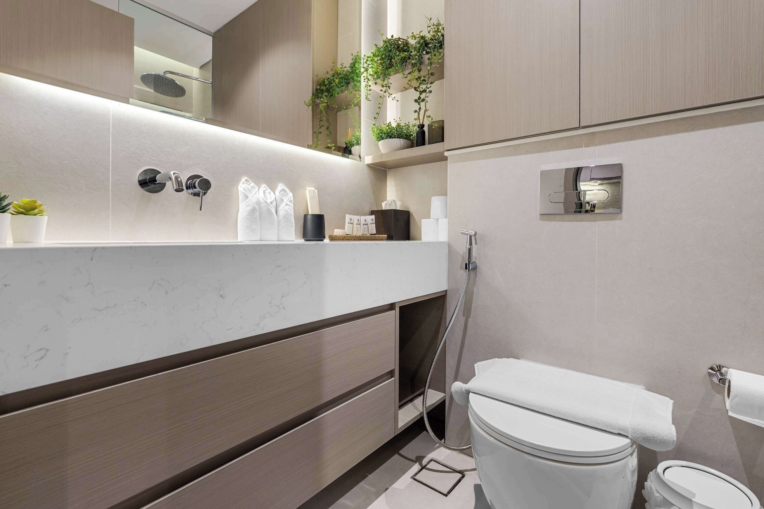 Uma casa de banho moderna com lavatório de mármore, sanita e chuveiro.