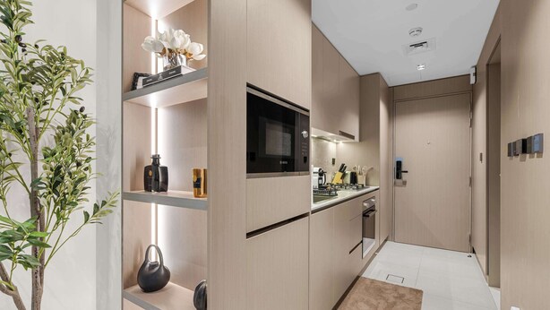A modern kitchen with built-in appliances, a central island, and a plant on the left. - Arjan Studio with Pool View, Jogging Track & BBQ (Arjan)