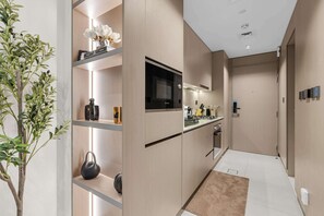 A modern kitchen with built-in appliances, a central island, and a plant on the left. - Arjan Studio with Pool View, Jogging Track & BBQ (Arjan)
