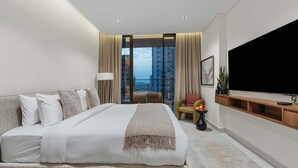 A modern hotel room with a large bed, a television, and a view of the city. - Arjan Studio with Pool View, Jogging Track & BBQ (Arjan)