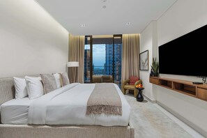A modern hotel room with a large bed, a television, and a view of the city. - Arjan Studio with Pool View, Jogging Track & BBQ (Arjan)