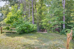 A forested area with a wooden bench and a rustic wooden structure.