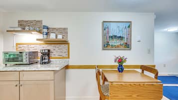 Una cocina compacta con cafetera, tostadora y un cuadro en la pared.