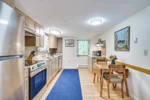 A modern kitchen with a built-in oven, a dining area with a wooden table and chairs, and a window with a view.