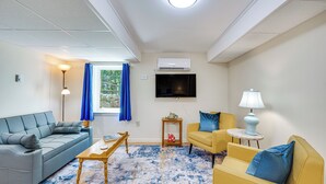 A living room with a sofa, armchair, coffee table, and a TV mounted on the wall. - Ashland Home w/ Deck - Blueberry Overlook (Ashland)