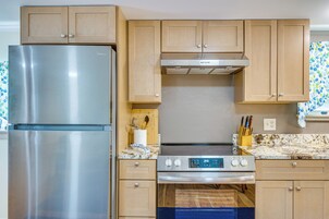 Una cocina con armarios de madera, un refrigerador de acero inoxidable, un horno empotrado y un microondas.