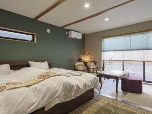 A hotel room with a large bed, a seating area with a table, and a view of the outdoors. - Kagoya mizunoto Auberge (Miyazu)