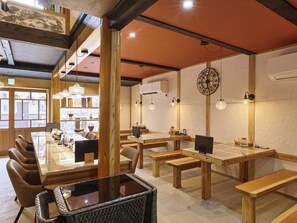 A dining area with wooden tables and chairs, pendant lighting, and a large clock on the wall. - Kagoya mizunoto Auberge (Miyazu)