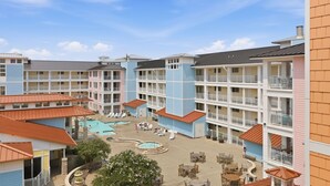 Een hotel met meerdere verdiepingen, met een binnentuin en een zwembad met ligbedden.