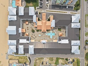 Luchtbeeld van een hotel met meerdere gebouwen, een zwembad en een parkeerplaats.