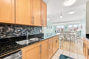 Eine moderne Küche mit Holzschränken, einer schwarzen Granit-Arbeitsplatte und einer Rückwand mit Mosaikfliesen.