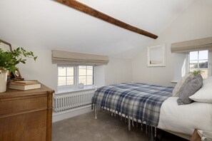 A bedroom with a bed, a radiator, a window, and a plant. - Top House -  a country house that sleeps 8 guests  in 4 bedrooms (Shipton-under-Wychwood)