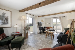 Ein Wohnzimmer mit Kamin, Fernseher und Essbereich inklusive Tisch und Stühlen.