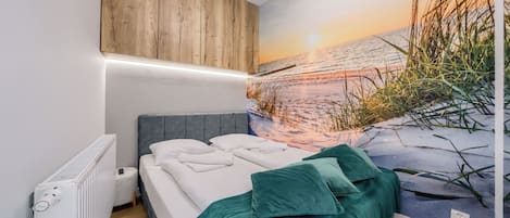 A bedroom with a bed, a radiator, a wooden panel wall, and a beach mural.