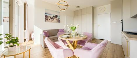 A modern dining area with a round table, pink chairs, and a minimalist design.