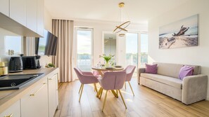 A modern living room with a dining area, a sofa, and a TV. - Apartamenty Sun & Snow Baltic Marina (Kołobrzeg)