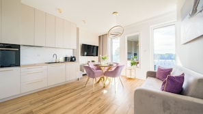 A modern kitchen with a dining area, a sofa, and a TV. - Apartamenty Sun & Snow Baltic Marina (Kołobrzeg)
