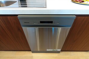 A stainless steel dishwasher with a digital control panel, located in a kitchen with wooden cabinets and a countertop. - bnbme - La Voile 1 - 1BR (Dubai)