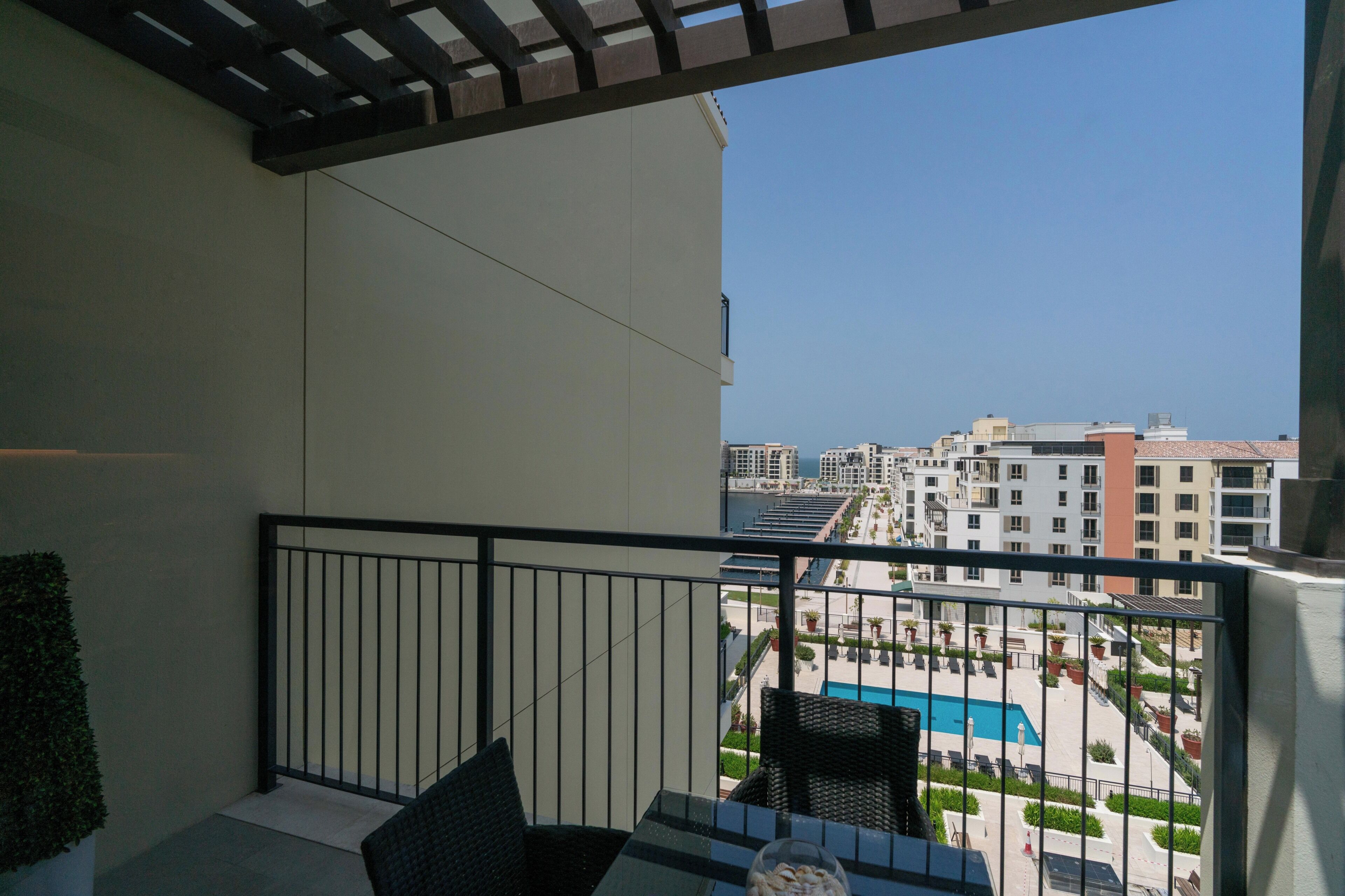 A balcony with a view of a swimming pool and surrounding buildings.