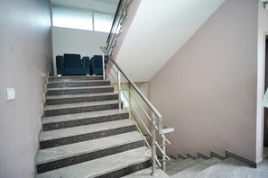 Una escalera con barandillas, escalones alfombrados y vista a una habitación con cama y ventana.
