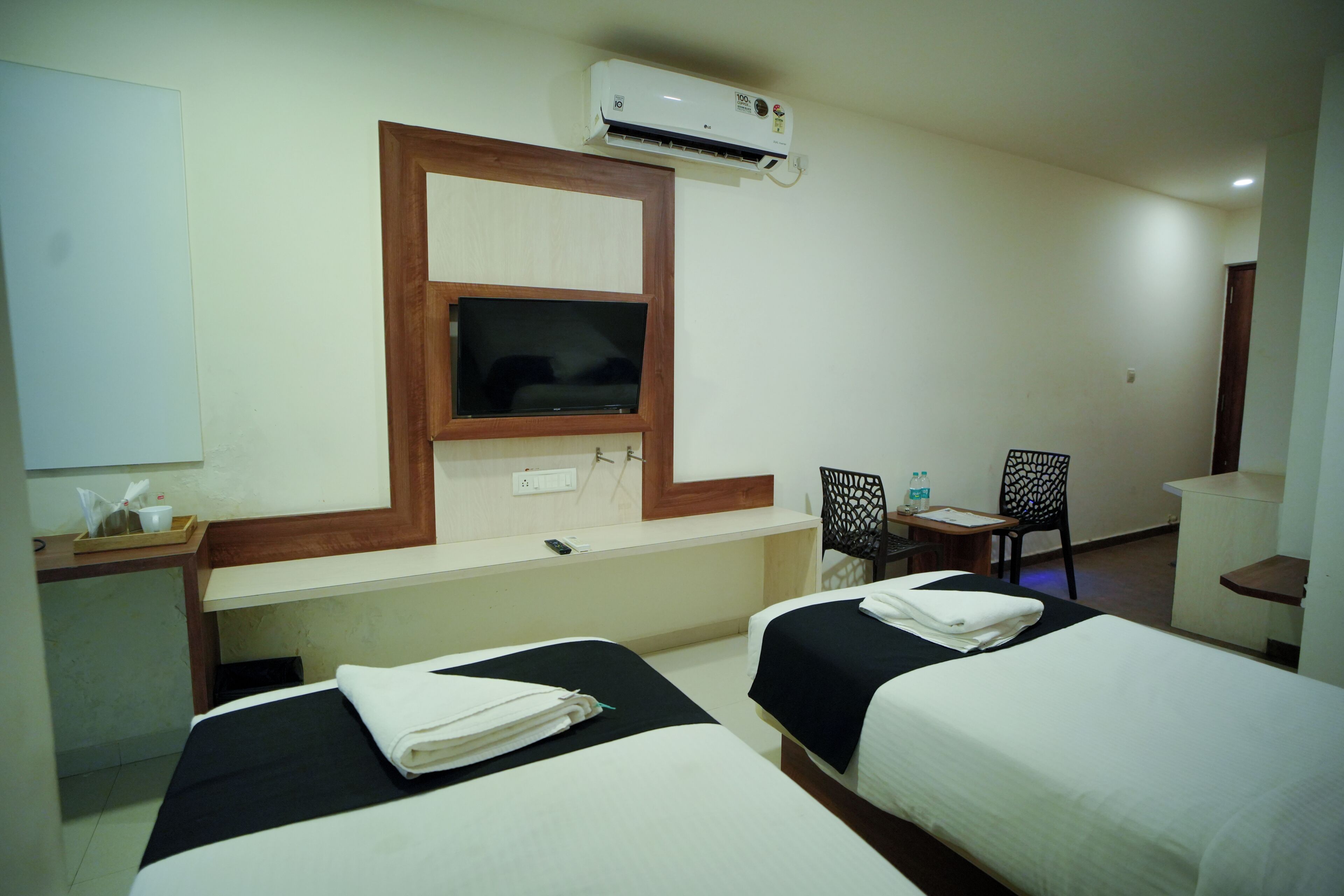 A hotel room with two beds, a TV, a desk, and a chair.