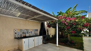Ein Außenbereich mit Küche, einer gefliesten Spritzwand, einem Grill und einer Pergola.
