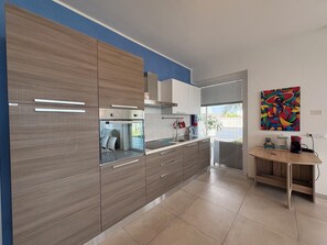 Eine moderne Küche mit Holzausstattung, einem Backofen und einem Fenster mit Blick auf einen Balkon.