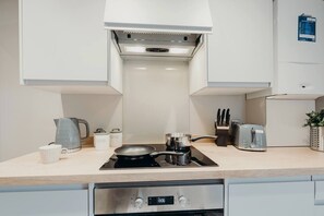 A modern kitchen with a built-in stove, a kettle, a toaster, and a knife block. - #38 Stylish Apart. 2|sleeps 4|5mins TamworthCastle (Staffordshire)