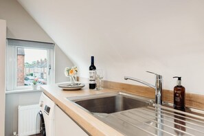 Eine Küche mit Fenster, einer Weinflasche und einer Handseifenflasche.