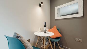 A small dining area with a round table, two chairs, a wine bottle, and a candle.